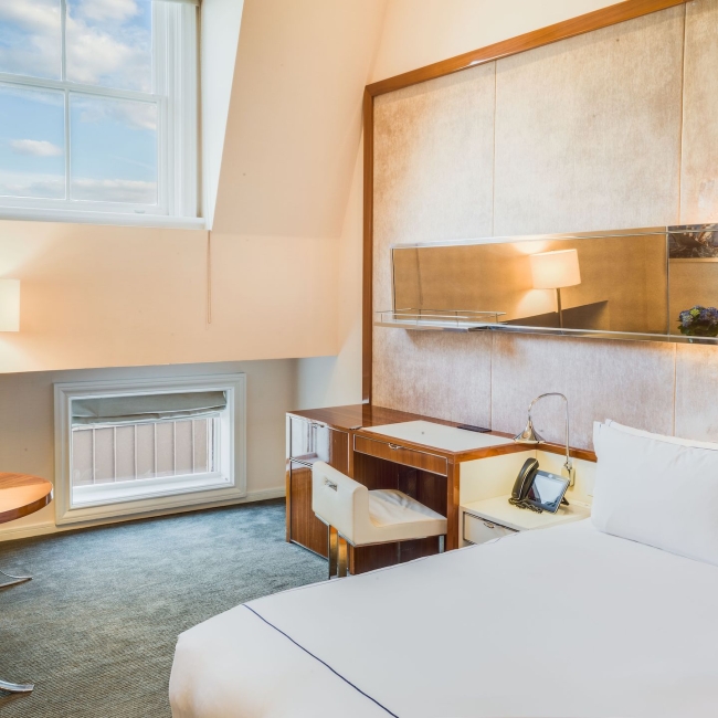 room with king bed with white linen and large windows and vaulted ceilings