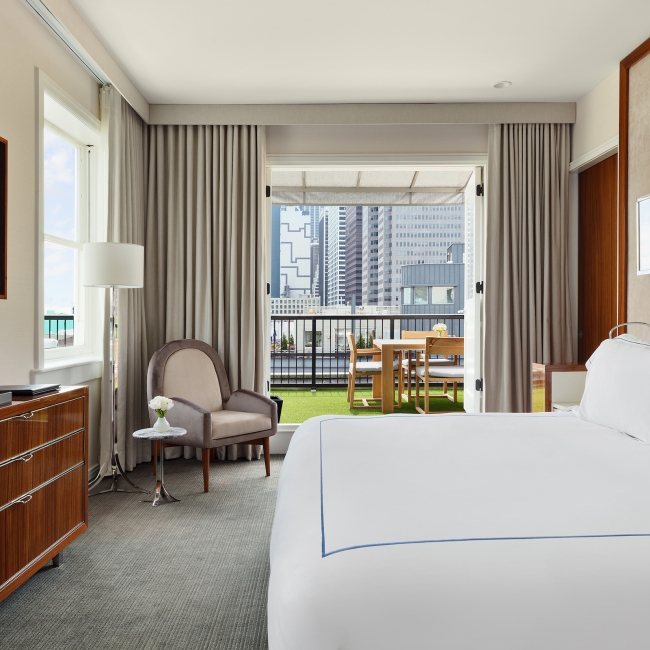 Large bedroom with white linen on bed, with a private terrace