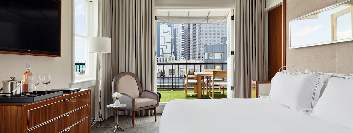 large bedroom with white linen and a private terrace